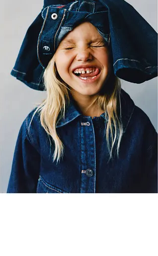 Lifestyle image of a child in denim with a playful fashion pose.