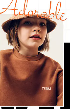 Child model in a rust-toned sweatshirt and woven bucket hat.